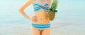 Summer vacation, close up beautiful young woman in bikini swimsuit with two pineapples in sunglasses on the beach on sea coast Royalty Free Stock Photo