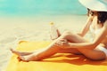 Summer vacation, close up of woman sunbathing and applying suntan cream on her legs lying on sand on the beach Royalty Free Stock Photo