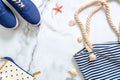 Summer vacation composition. Fashionable blue sneakers, striped beach bag, seashells, sea star on marble background. Women`s desk Royalty Free Stock Photo