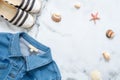 Summer vacation composition. Fashionable jeans jacket, striped summer sandals, seashells, sea star on marble background. Women`s d