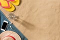 Summer vacation composition. Flip flops, hat and glass of water on sand background