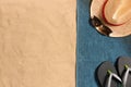 Summer vacation composition. Flip flops, hat and sunglasses on sand background