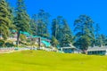 Summer Vacation Concept Cottages surrounded with Green trees and green grass near public park with tall trees light blue sky Royalty Free Stock Photo