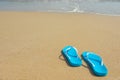 Tropical summer vacation concept. Flipflops on a sandy ocean beach. Blue beach shoes on the sandy seashore. Royalty Free Stock Photo