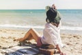 Summer vacation concept. Happy young woman relaxing on beach. Hipster slim girl in white shirt and hat sitting and tanning on Royalty Free Stock Photo