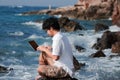 Summer vacation concept. Lifestyle Asian man with laptop relaxing at blue sea shore. Royalty Free Stock Photo