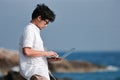 Summer vacation concept. Lifestyle Asian man with laptop relaxing at blue sea shore. Royalty Free Stock Photo