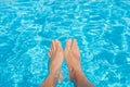 Man`s feet against blue water of swimming pool Royalty Free Stock Photo