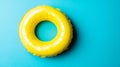 A summer vacation concept is represented by the image of a yellow inflatable ring floating against a vibrant blue Royalty Free Stock Photo