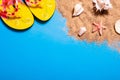 Summer vacation concept with seashells, starfish and women`s beach sandals on a blue background and sand. Royalty Free Stock Photo