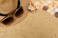 Summer vacation concept with seashells, women`s beach hat and sunglasses on sand background. Royalty Free Stock Photo