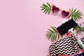 summer vacation concept. stylish pink sunglasses, modern swimsuit, phone on selfie stick, and green palm leaves on pink Royalty Free Stock Photo