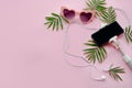 summer vacation concept. stylish pink sunglasses, phone on selfie stick, headphones, and green palm leaves on pink background, fl Royalty Free Stock Photo