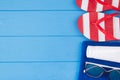 Summer vacation concept. Top above overhead view close-up photo of towel sunglasses sunscreen and flipflops isolated on blue