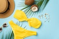 Summer vacation concept. Top view photo of sunhat coconuts shell bracelet and earrings sunglasses yellow swimwear and palm leaves Royalty Free Stock Photo