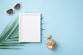 Summer vacation concept. Top view photo of white photo frame sunglasses shells and palm leaves on isolated pastel blue background Royalty Free Stock Photo