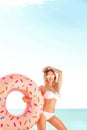 Summer Vacation. Enjoying suntan woman in white bikini with donut mattress near the sea. Royalty Free Stock Photo