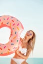 Summer Vacation. Enjoying suntan woman in white bikini with donut mattress near the sea. Royalty Free Stock Photo