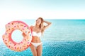 Summer Vacation. Enjoying suntan woman in white bikini with donut mattress near the swimming pool. Royalty Free Stock Photo