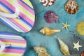 Summer vacation feelings concept: top view on isolated colorful striped flip flops with seashells on blue background