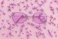 summer vacation and festival concept. stylish purple boho sunglasses on pink background with lilac flowers. creative trendy flat Royalty Free Stock Photo