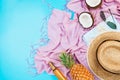 Summer vacation flatlay with straw hat, pink scarf, pineapple, coconut, body oil and glasses