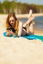Summer vacation Girl with phone tanning on beach Royalty Free Stock Photo