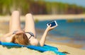 Summer vacation Girl with phone tanning on beach Royalty Free Stock Photo