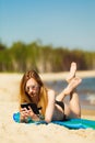 Summer vacation Girl with phone tanning on beach Royalty Free Stock Photo