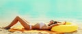 Summer vacation, happy relaxing slim young woman lying on sand on the beach with swimming inflatable ring on sea background Royalty Free Stock Photo