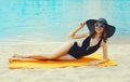 Summer vacation, happy relaxing young woman in bikini and straw hat lying on sand on the beach on sea background Royalty Free Stock Photo