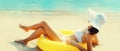 Summer vacation, happy relaxing young woman lying on sand on the beach with swimming inflatable ring on sea background Royalty Free Stock Photo