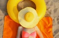 Summer vacation, happy relaxing young woman with straw hat covering her face lying on sand on the beach with swimming inflatable Royalty Free Stock Photo