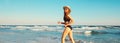 Summer vacation, happy smiling woman walking running in bikini swimsuit and straw hat on the beach on sea coast with waves Royalty Free Stock Photo