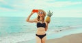 Summer vacation, happy smiling young woman holding pineapple taking selfie with smartphone wearing bikini swimsuit and straw hat Royalty Free Stock Photo