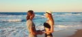 Summer vacation, happy young couple looking at each other holding hands on the beach in warm evening summer day on sea coast Royalty Free Stock Photo