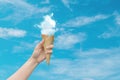 Woman hand holding Ice cream cone with white cloud with blue sky in background. Royalty Free Stock Photo