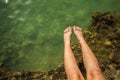 Summer vacation holidays concept of female feet on rock stones above sea shore water vivid water surface, copy space