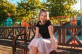 Summer vacation. Portrait of a beautiful young woman is sitting on a Park bench, smiling playfully and looking away. Sunny Royalty Free Stock Photo