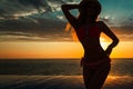 Summer Vacation. Silhouette of beauty dancing woman on sunset near the pool with ocean view. Royalty Free Stock Photo