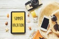 summer vacation text sign on yellow tablet screen. planning summer holiday flat lay, camera sunglasses passport money phone hat