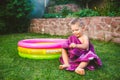 Summer vacation theme. A small 3 year old Caucasian boy playing in the backyard of a house on the grass near a round inflatable co Royalty Free Stock Photo