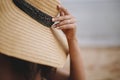 Summer vacation and travel. Girl sitting on beach, hand holding hat close up. Fashionable young woman in straw hat relaxing on Royalty Free Stock Photo