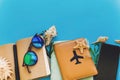 summer vacation and travel image. stylish black phone, passport, sunglasses, map, shells,notebook with pen on trendy blue paper.