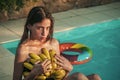 Summer vacation and travel to ocean. woman with tropical fruit in pool. Vitamin in banana at girl sitting near water Royalty Free Stock Photo