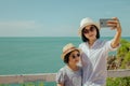 Asian woman and girl standing relax on cliff nearly seashore, They taking selfie together. Royalty Free Stock Photo