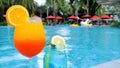 Summer vacation. Two glasses of tropical iced drinks on poolside with fun people Royalty Free Stock Photo