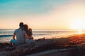 Summer vacation. A young couple posing against the sea, sitting on the rocks in an embrace. Rear view. Copy space. Sunset Royalty Free Stock Photo