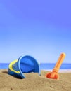 Summer vacations. Bucket with accessories on a sandy beach. Blur sea background Royalty Free Stock Photo