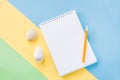 Summer vacations concept with yellow stripe, white notepad, orange pen and two seashells on blue-green background. Royalty Free Stock Photo